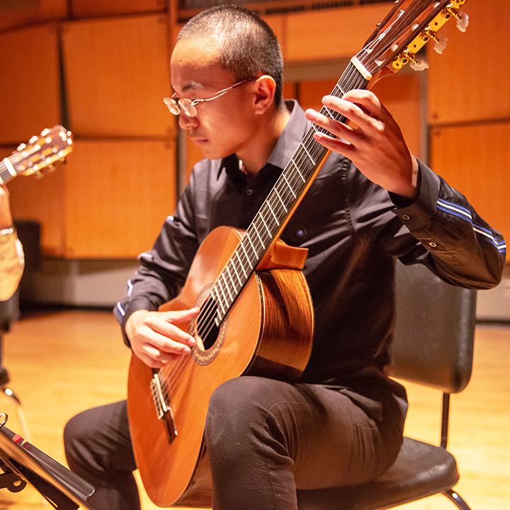 Student playing guitar on stage