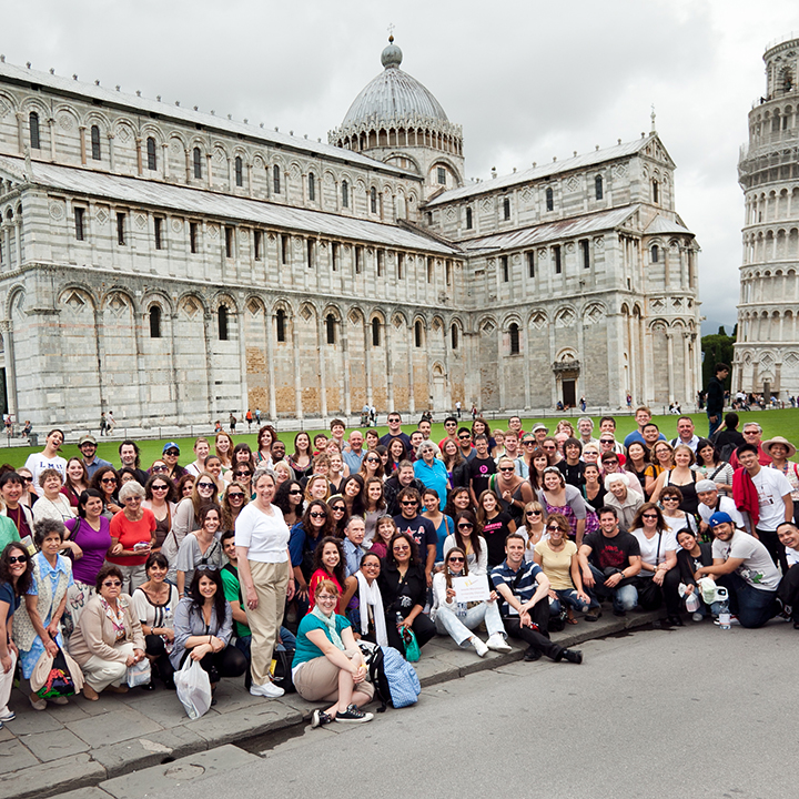 A choral group standing in front of the Tower of Pisa