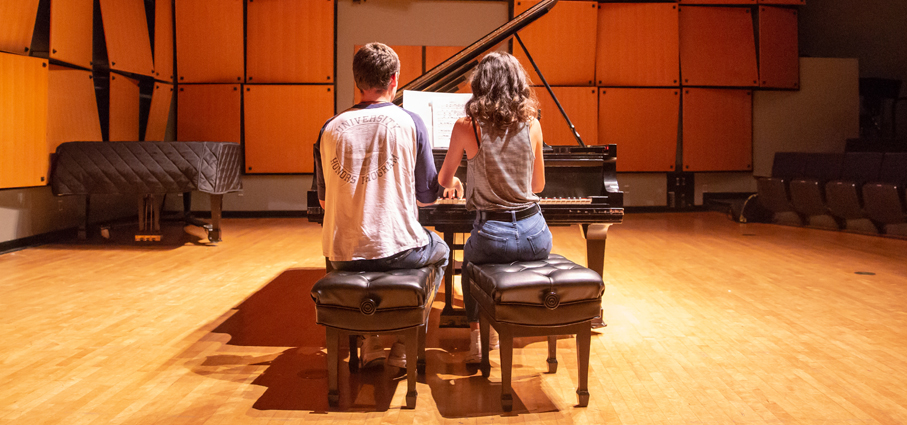 Two students playing the piano together in Murphy Recital Hall.