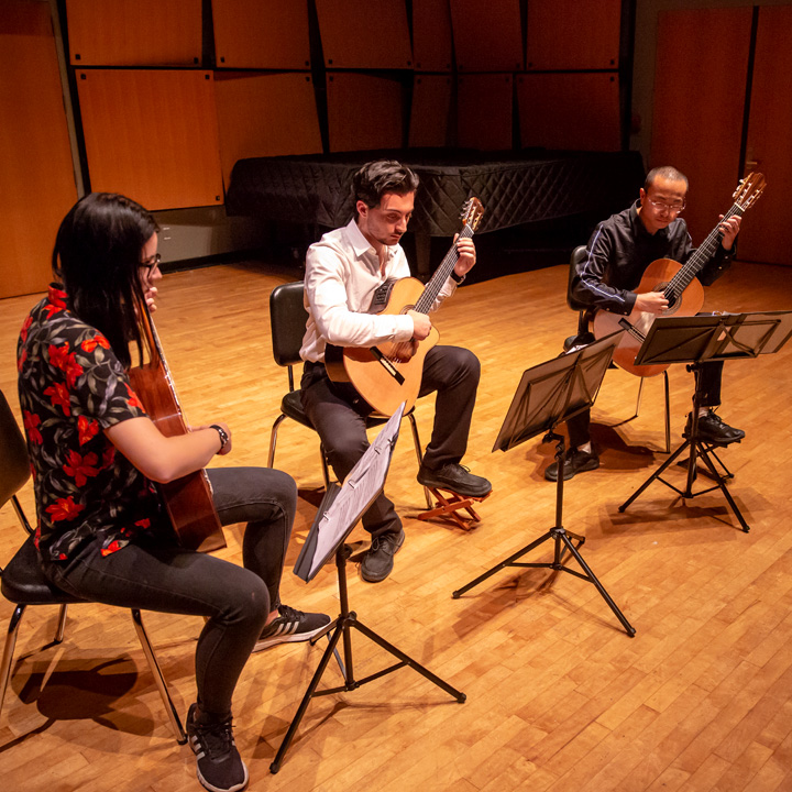 Three guitarists playing together in Murphy Recital Hall.