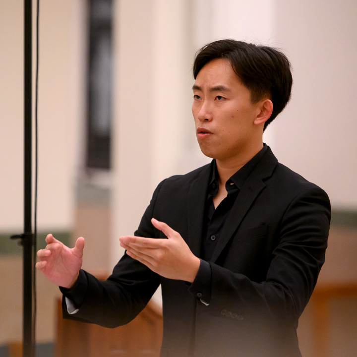 A conductor guiding the LMU Choirs during a performance in Sacred Heart Chapel.