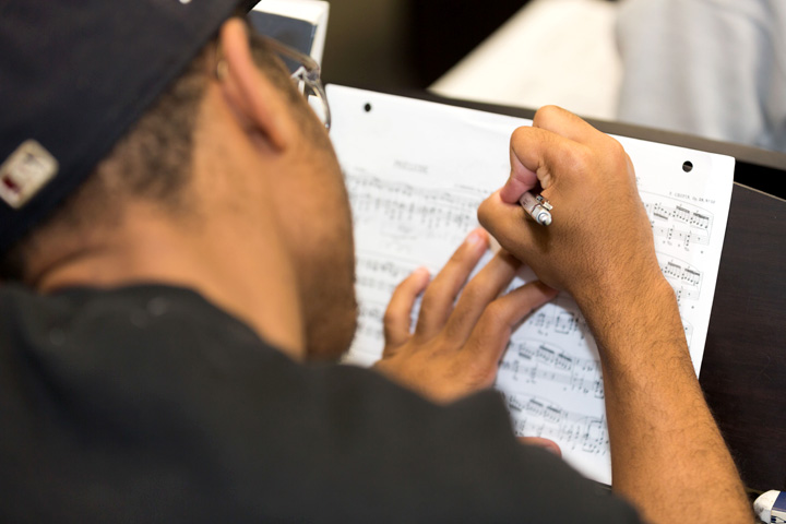 Over the shoulder view of a music student working on an assignment during a class.