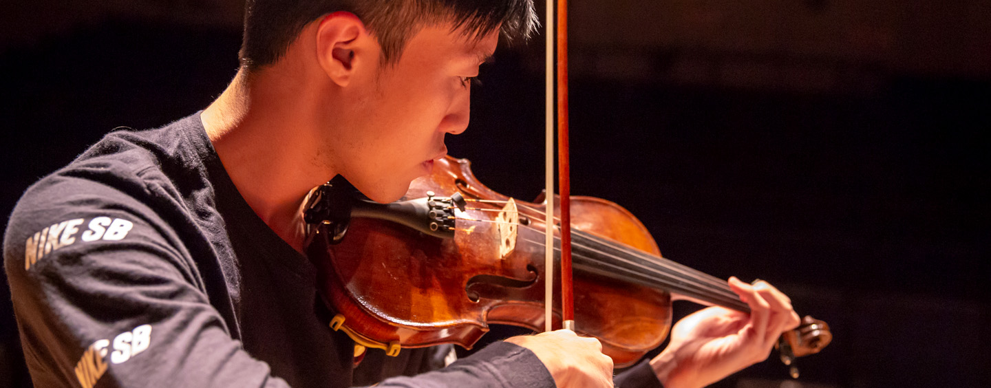 A student playing the violin in the recital hall.