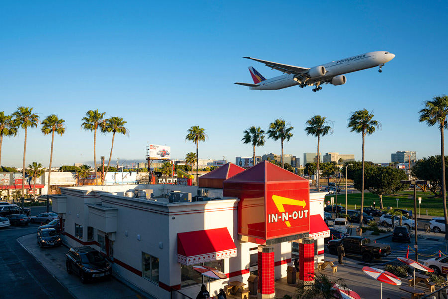 An airplane preparing to land at LAX, with In-N-Out in the foreground.
