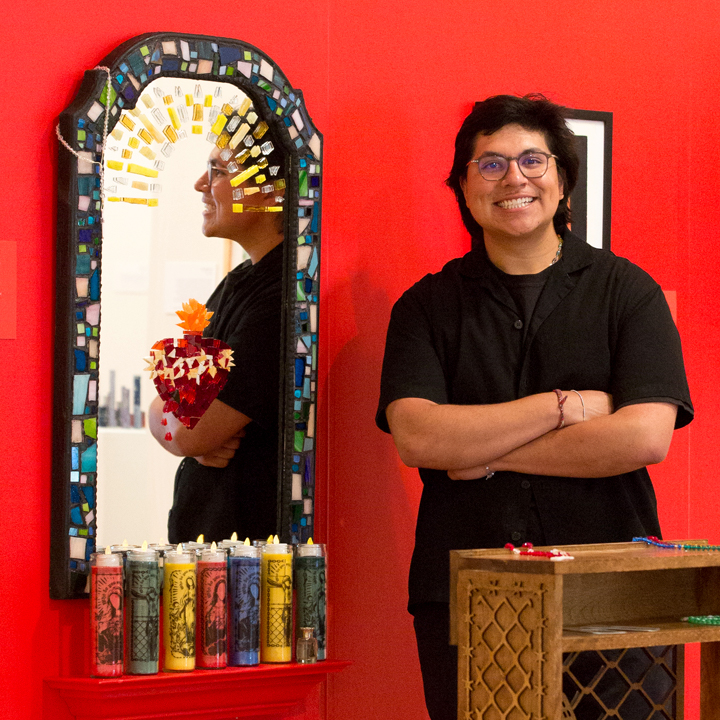 A student posing for a photo with his graphic design thesis project.