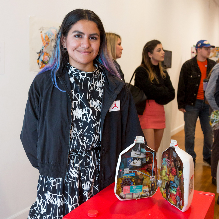 A student standing next to her artwork on display at the Laband Gallery.