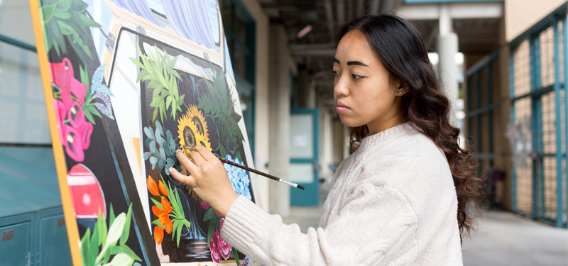 A student painting an image outside of the studio.