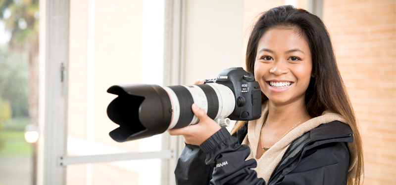 A student posing with a camera.