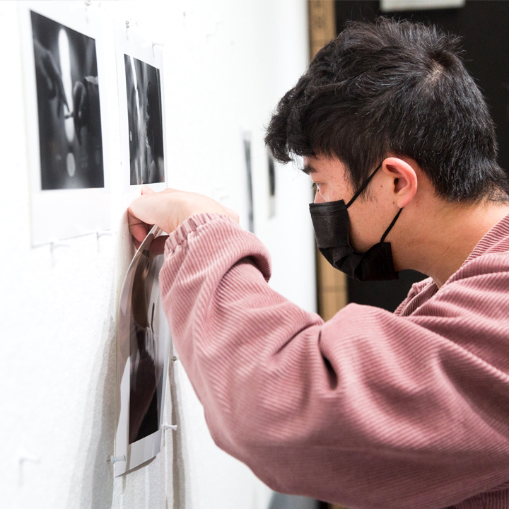 A photo student pinning work onto the wall during class.