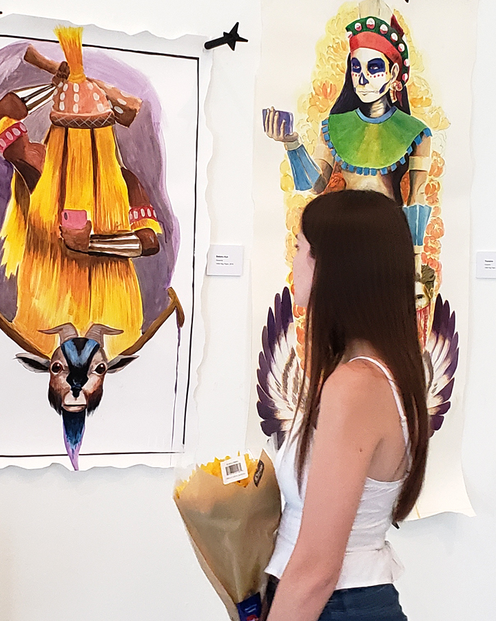 A gallery visitor looks at artwork at the 2019 Fine Arts Senior Thesis Exhibition.