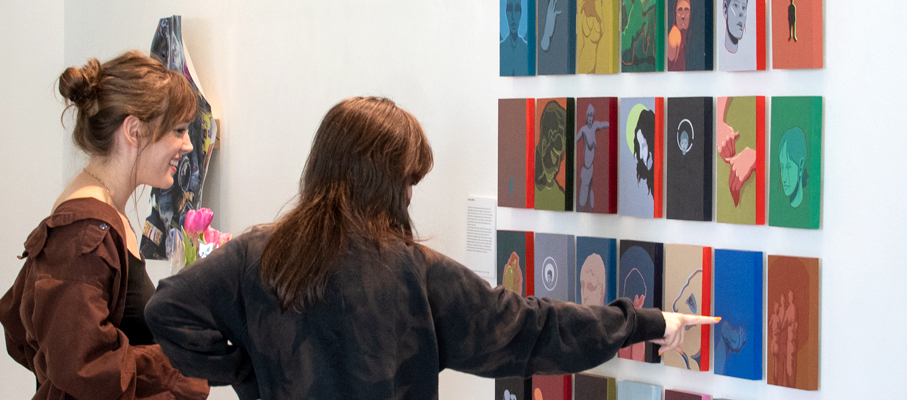 Two people looking at artwork at the 2022 Fine Arts and Multimedia Arts Senior Exhibition.