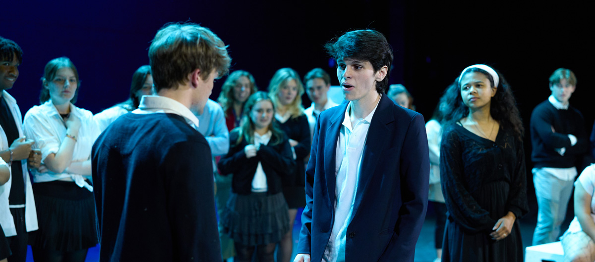 Two students speaking while other students watch.