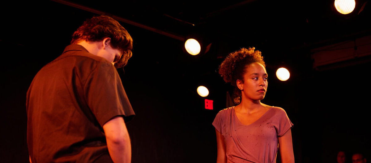 Two people talking to each other, in a room lit in orange.