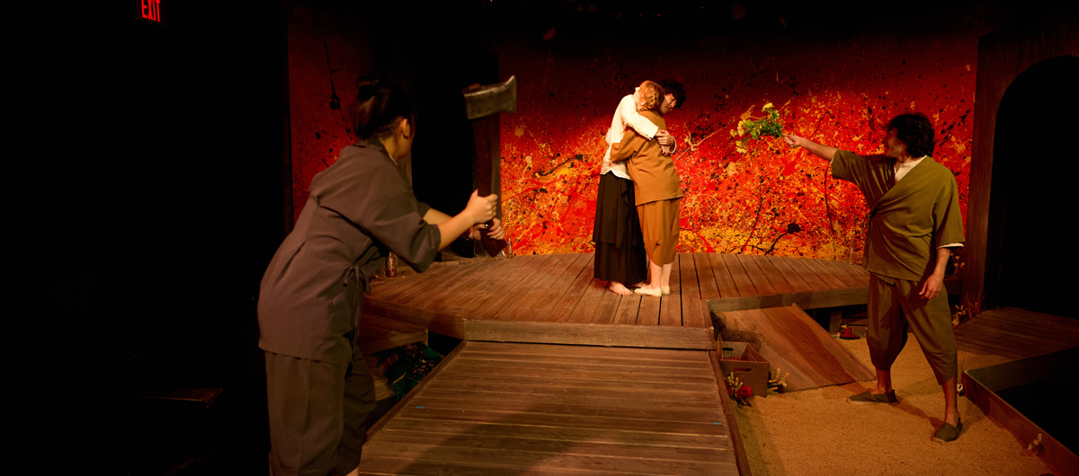 An axe-wielding woman confronts an outsider, while two others offer a hug and flowers.