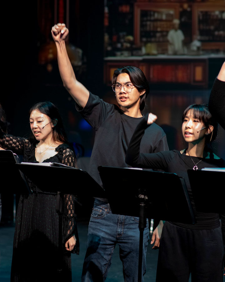 Three people with their fists raised, dressed in black.