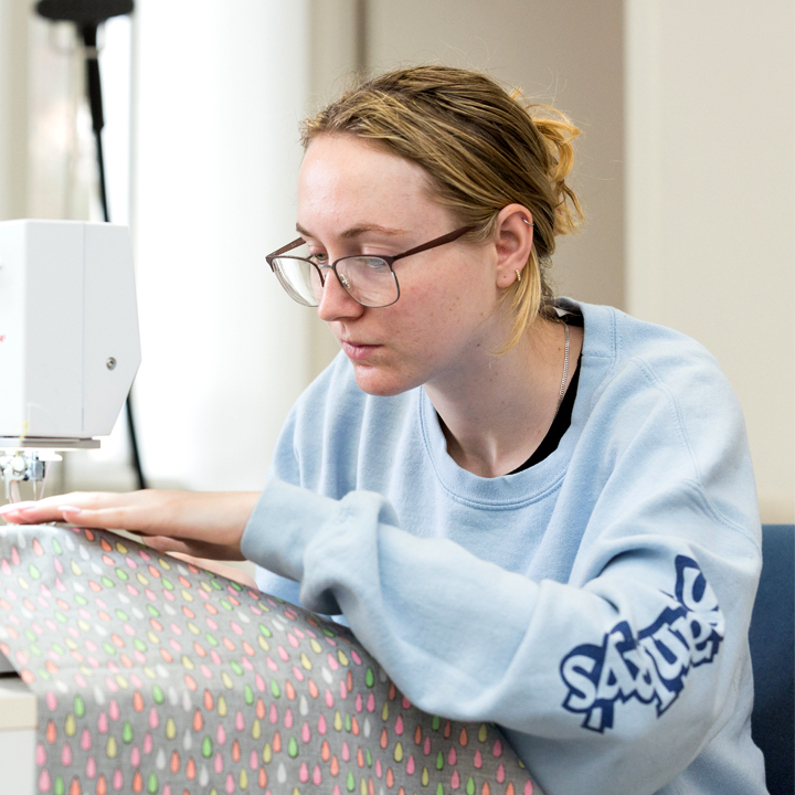 A student using a sewing machine in the costume shop.