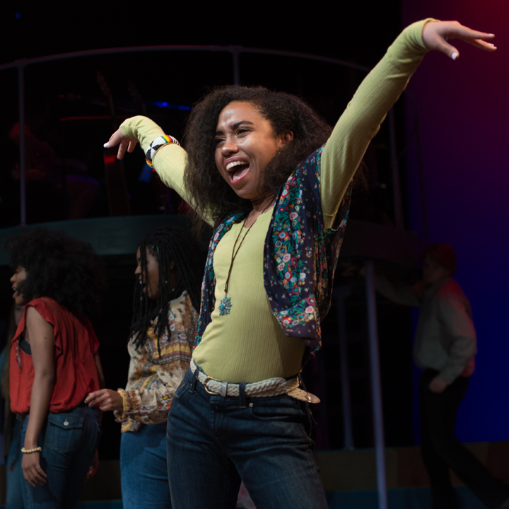 A group of students performing onstage in Hair.