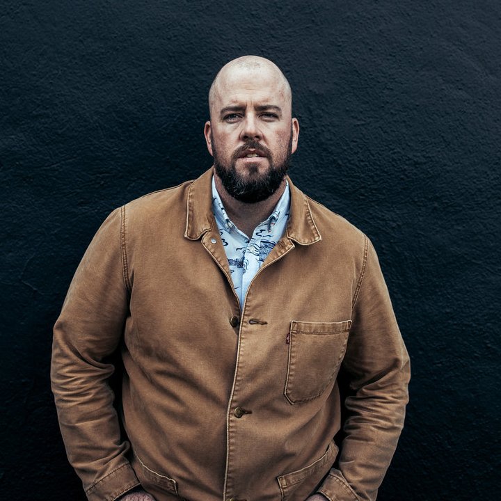 A picture of Chris Sullivan standing in front of a dark wall.