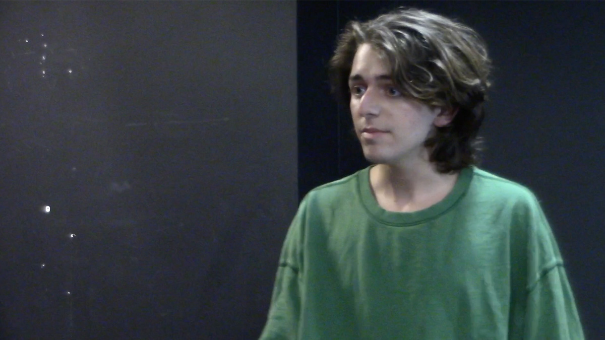 Alexandre Akhavein performing in a scene, dressed in a green shirt.