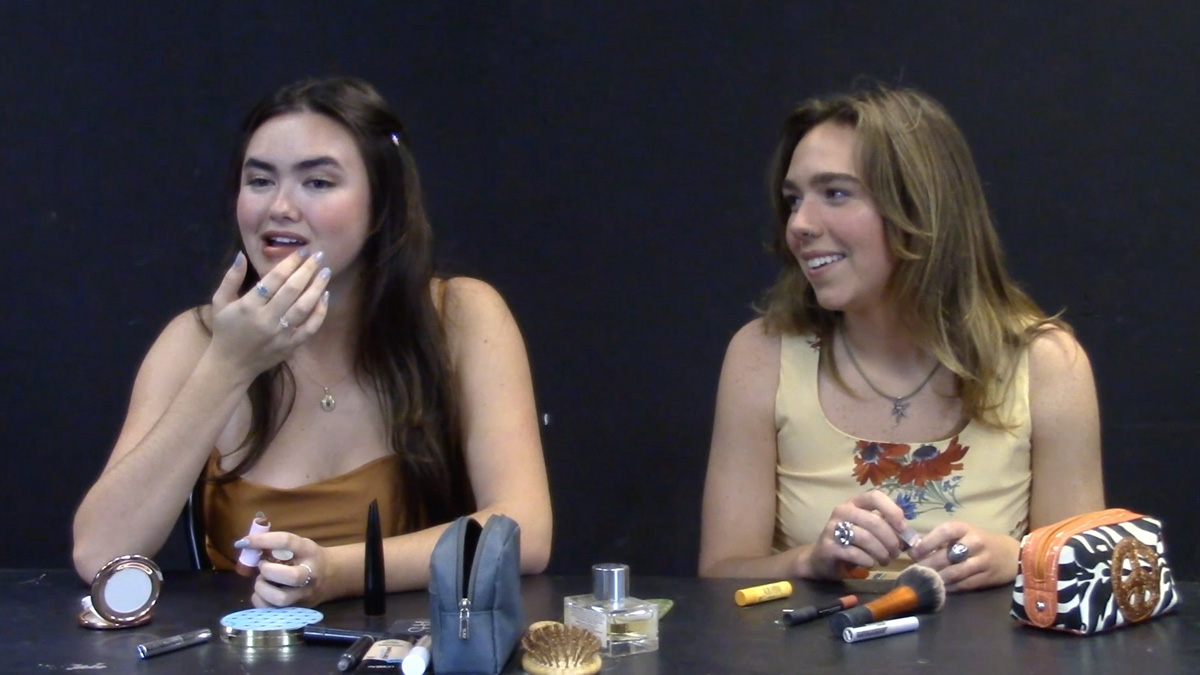 Sara Bunge talking to another woman while putting on makeup.