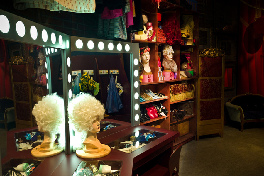 A collection of wigs and outfits in a dressing room.