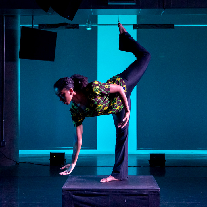 A dancer performing in a studio with blue lighting.